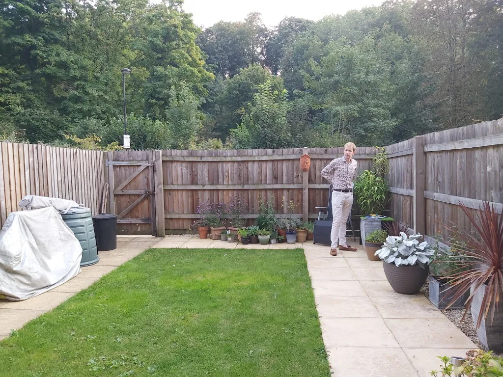 The Small Budget Garden — Before A patch of lawn surrounded by slabs and a high fence