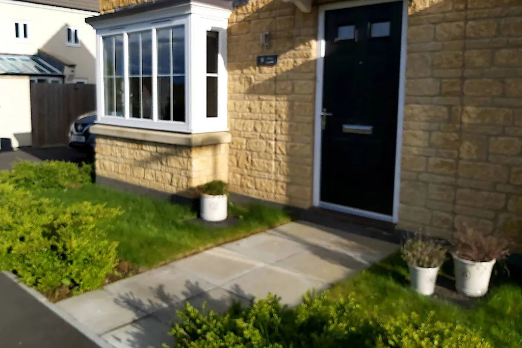 Before A small area of plain lawn and simple shrubs in front of a house.