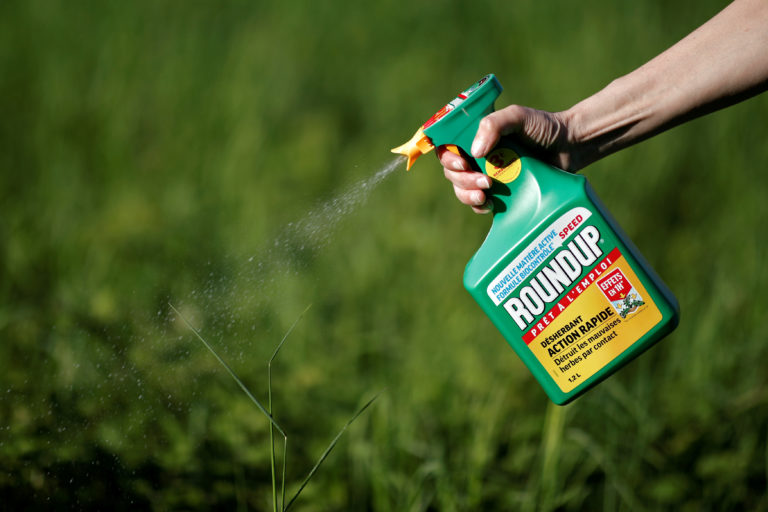 A bottle of Roundup being sprayed